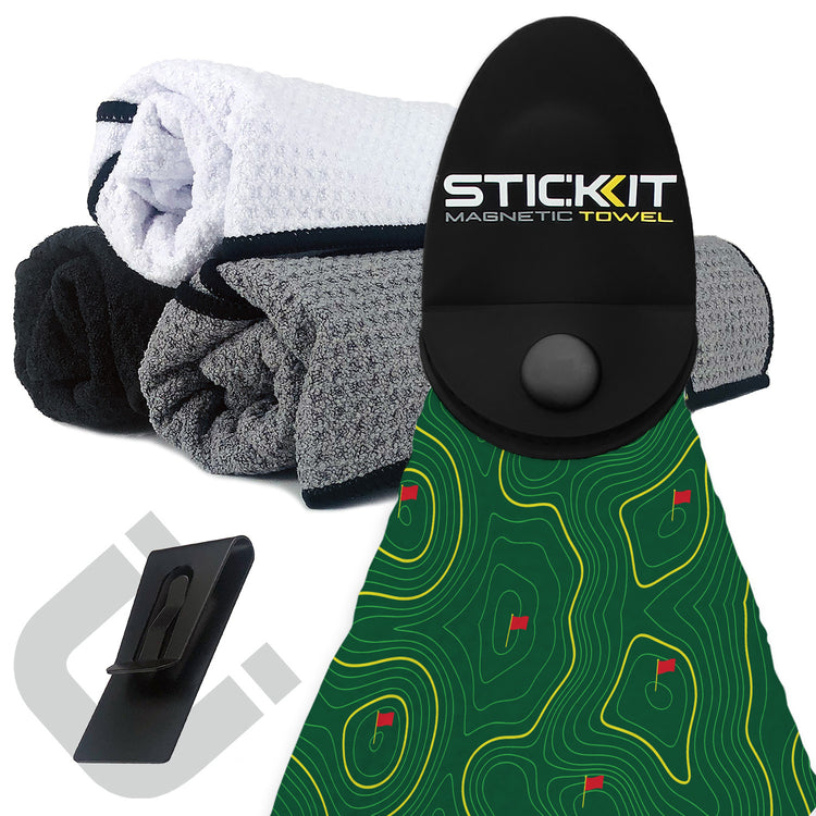 Magnetic golf towel with green terrain design, black holder, and multi-color microfiber towels stacked beside it.