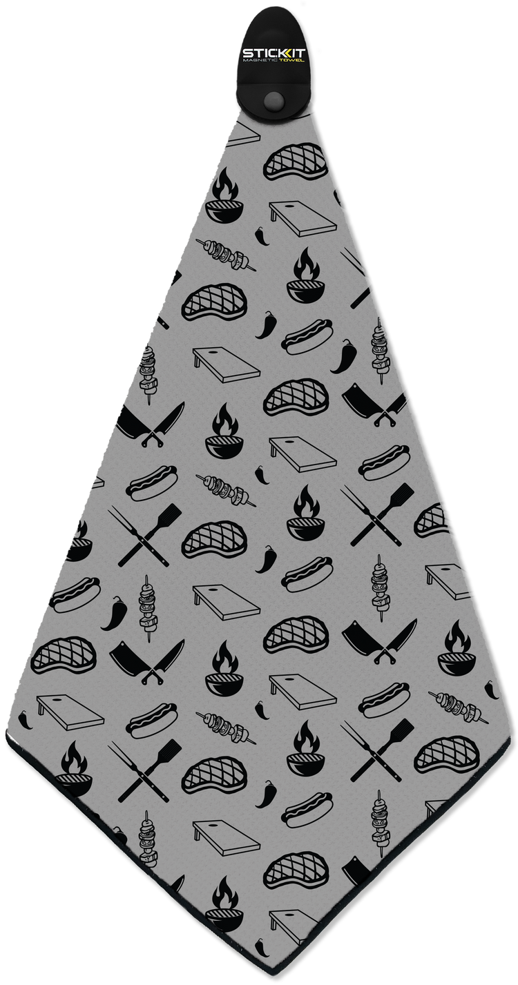 Gray kitchen towel with black cooking-themed patterns, including grill icons, knives, and flames, made from durable fabric.