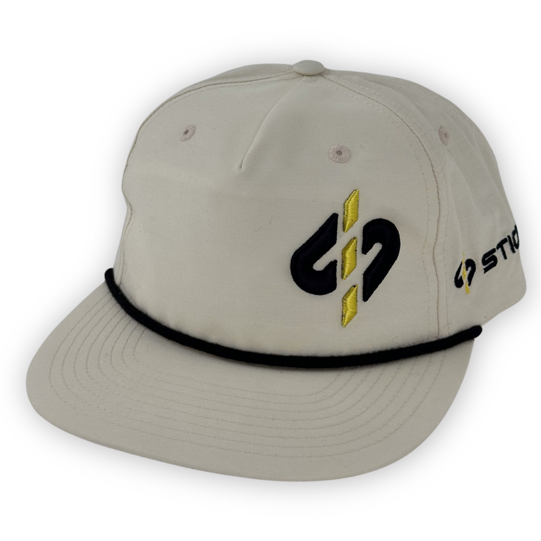 Beige snapback cap with black and yellow logo, featuring a classic design and adjustable strap.