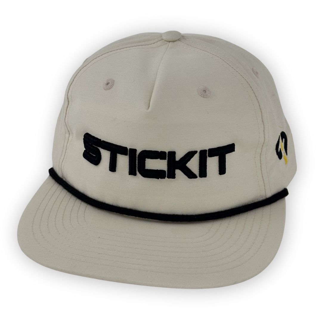 Beige cotton cap featuring black "STICKIT" embroidery and a black trim. Perfect for casual outdoor wear.