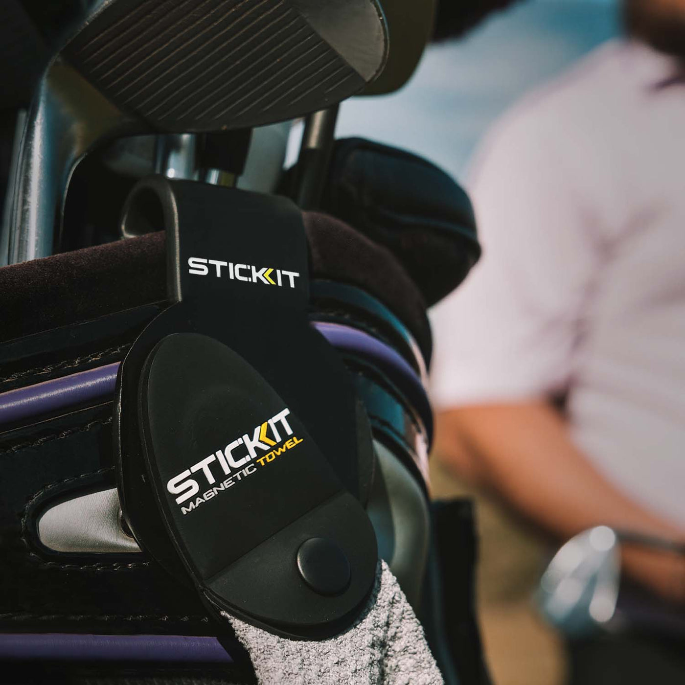 Black magnetic golf towel holder with STICKIT branding, designed for easy attachment to golf bags.